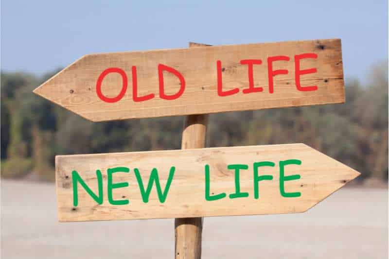 Holz-Schild als Wegweiser, ein Pfeil nach links mit roter Schrift "Old Life," ein Pfeil nach Links mit grüner Schift "New Life" als Darstellung von Neuorientierungsphasen im Rahmen von Persönlichkeitsentwicklung